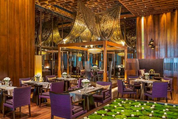 Innenbereich des Siam Kempinski Hotel Bangkok mit Restaurant, Tischen und Lotusteich.