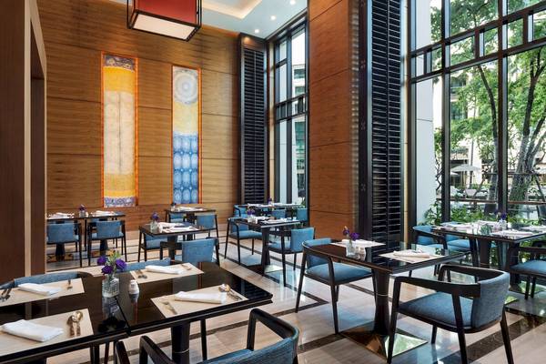 Restaurantbereich im Siam Kempinski Hotel Bangkok mit blauen Stühlen und Tischen.