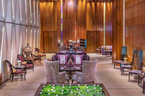 Lobby des Siam Kempinski Hotels in Bangkok mit Holzwänden, Möbeln und Lotus-Teich.