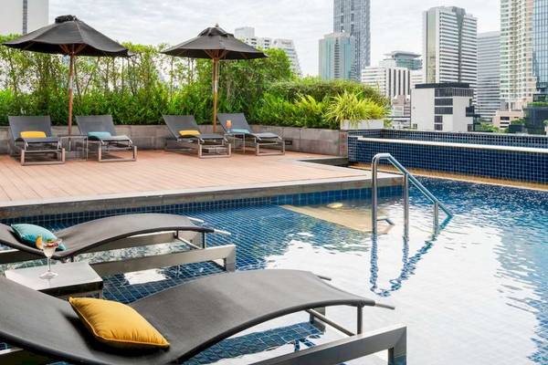 Pullman Bangkok Hotel G Poolterrasse mit Sonnenliegen, Sonnenschirmen und Blick auf die Stadt