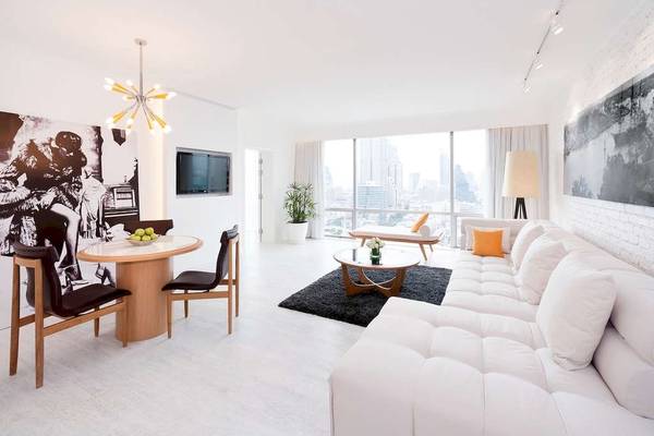 Modernes Wohnzimmer im Pullman Bangkok Hotel G mit weißem Sofa, Esstisch und Fernseher.