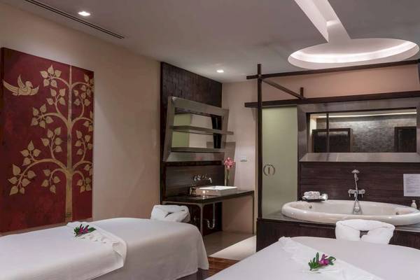 Spa-Behandlungsraum im Pullman Bangkok Hotel G mit zwei Massagebetten, einem Badezimmer und einer Badewanne.
