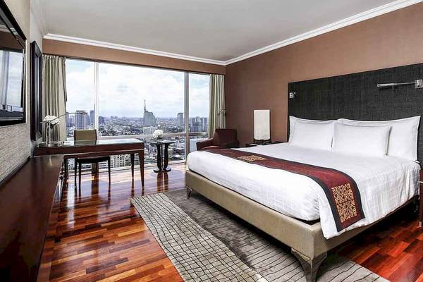 Innenansicht der Suite im Pullman Bangkok Hotel G mit großem Bett und Stadtblick