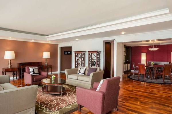 Innenansicht des Wohnzimmers im Pullman Bangkok Hotel G mit modernen Möbeln und Holzboden.