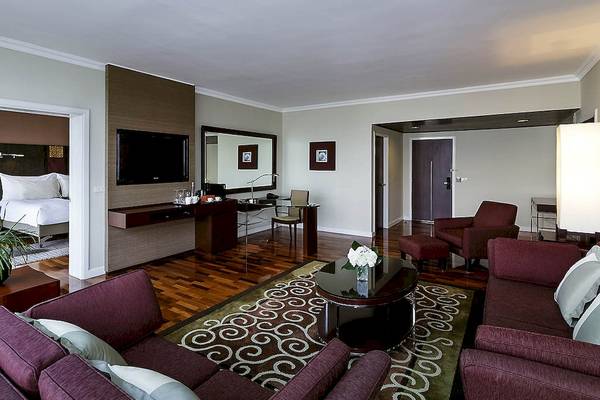 Innenansicht der Suite im Pullman Bangkok Hotel G mit Wohnzimmer, Schreibtisch und Schlafzimmerbereich.