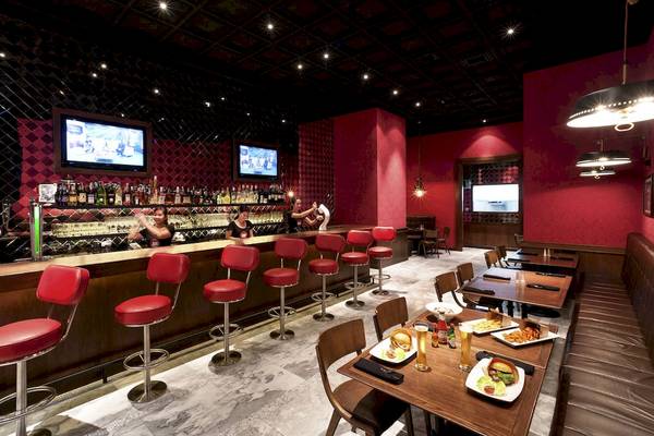 Innenbereich des Pullman Bangkok Hotel G mit roter Bar, Sitzstühlen und Essenstischen.