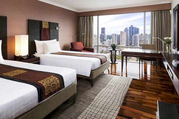Zwei Betten in einem modernen Hotelzimmer des Pullman Bangkok Hotel G mit Blick auf die Stadt.