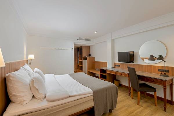 Innenansicht eines Hotelzimmers im Sunprime Kamala Beach mit Bett, Schreibtisch und Fernseher.