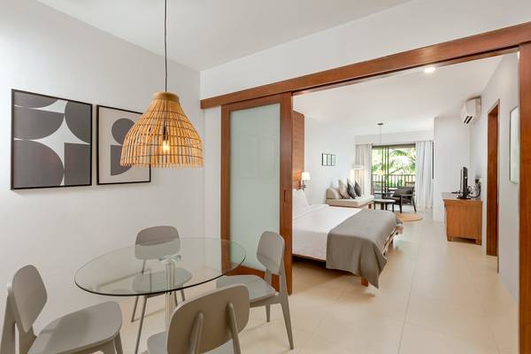 Innenansicht des Schlafzimmers im Sunprime Kamala Beach Hotel mit Doppelbett, Schreibtisch und Glastisch.