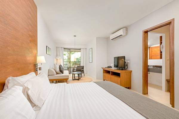 Innenansicht eines Hotelzimmers im Sunprime Kamala Beach mit Bett, Fernseher und Wohnzimmerbereich.