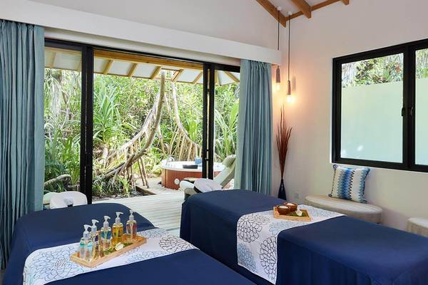 Spa-Behandlungsraum im Amari Havodda Maldives mit Blick auf einen Whirlpool im Freien.