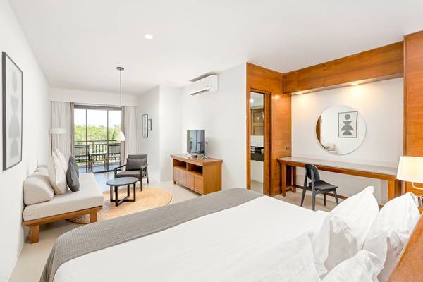 Schlafzimmer im Sunprime Kamala Beach Hotel mit Bett, Couch, Fernseher und Deko.