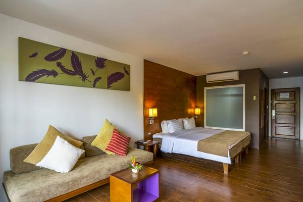 Hotelzimmer von Sunprime Kamala Beach mit Bett, Sofa, Nachttisch und Wandkunst.