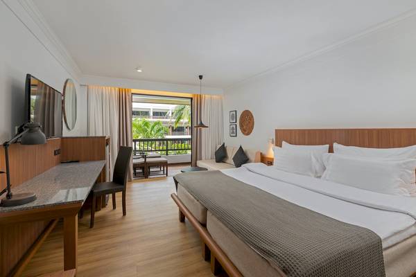 Schlafzimmer im Sunprime Kamala Beach Hotel mit Doppelbett, Schreibtisch und Balkonzugang.