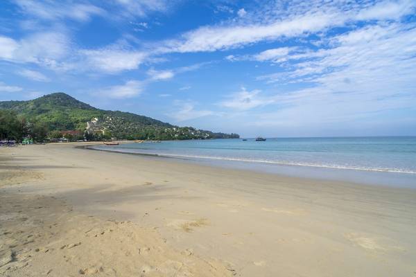 Sonnenklarer Strand am Kamala Beach mit einem Berg im Hintergrund.