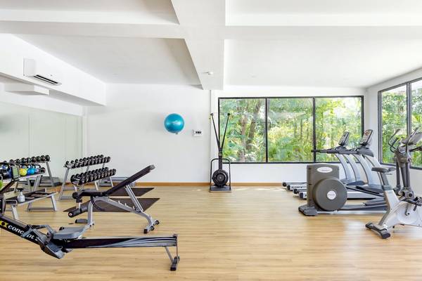 Fitnessstudio im Sunprime Kamala Beach mit verschiedenen Geräten und großen Fenstern.