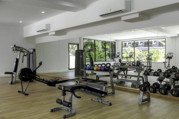 Fitnessraum im Sunprime Kamala Beach Hotel mit verschiedenen Trainingsgeräten und Spiegeln.