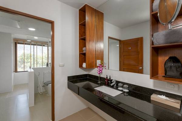 Badezimmer im Sunprime Kamala Beach Hotel mit schwarzem Granit und Holzschränken.