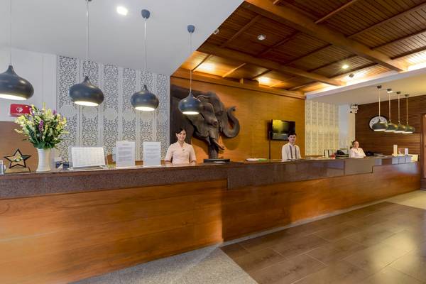 Hotelrezeption mit Elefanten-Wandbild und drei Mitarbeitern, die hinter dem Empfangstresen stehen.