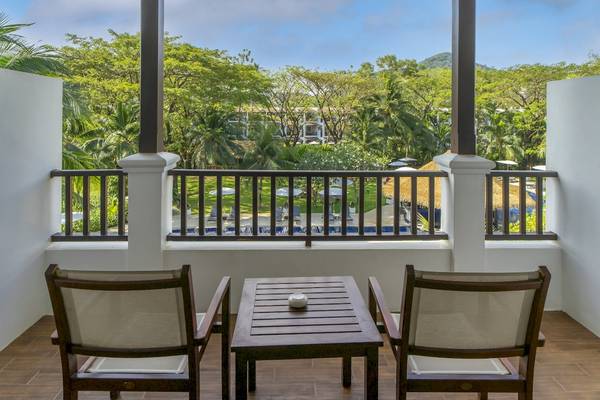 Ein Balkon des Sunprime Kamala Beach Hotels mit einem Tisch und zwei Stühlen.