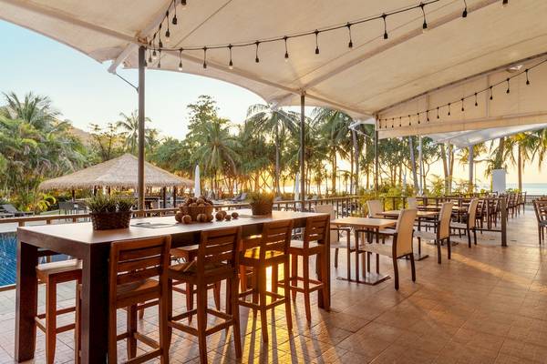 Terrasse des Sunprime Kamala Beach Hotels mit Tischen und Stühlen im Freien.