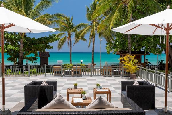 Terrasse des Sunprime Kamala Beach Hotels mit Blick auf den Ozean, Sonnenschirme und Loungemöbel.