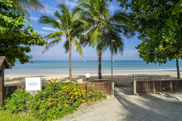 Strandansicht mit Palmen, Gehweg und Restauranteingang des Sunprime Kamala Beach.