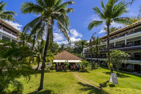 Außenbereich des Sunprime Kamala Beach Hotels mit Gebäuden, Rasen und Palmen.