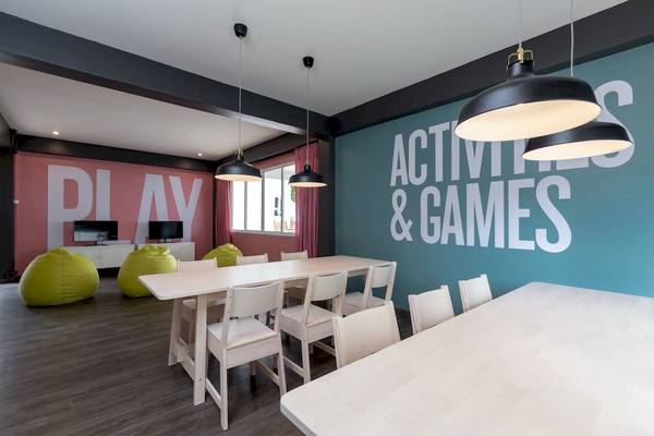 Spielzimmer im Sunwing Bangtao Beach Hotel mit Tischen, Stühlen, Hängelampen und bunten Sofas.