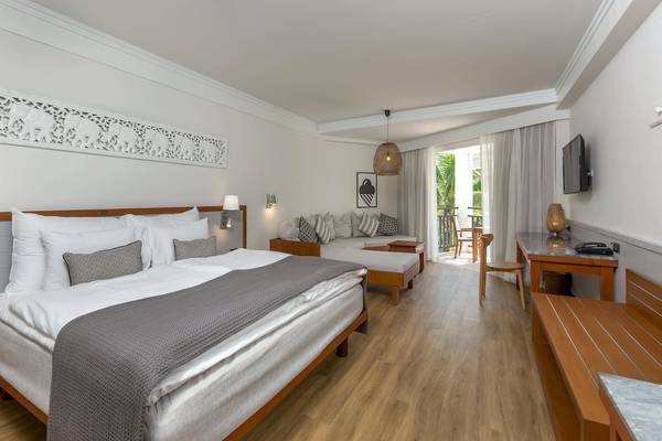 Hotelzimmer von Sunwing Bangtao Beach mit einem Bett, Wohnzimmer, Fernseher und Balkon.