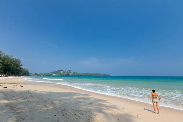Frau am Strand des Sunwing Bangtao Beach Hotels, Blick auf das Meer und eine Insel.