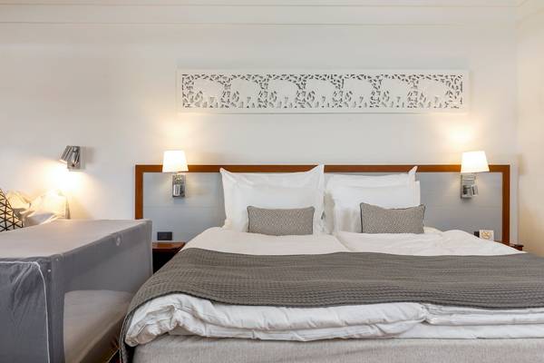 Hotelzimmer im Sunwing Bangtao Beach mit einem Doppelbett, weißen Kissen und grauer Bettdecke.
