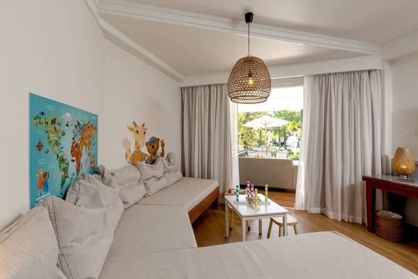 Wohnzimmer mit L-förmigem Sofa, Tisch, Lampe und Weltkarte an der Wand.