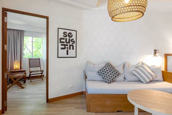 Hotelzimmer von Sunwing Bangtao Beach mit offenem Eingang, Couch, Tisch und Wanddekoration.