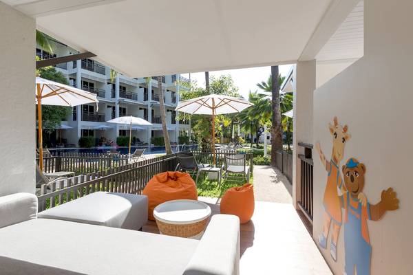 Terrasse des Sunwing Bangtao Beach Hotels mit Sonnenschirmen, Sofas und einem Swimmingpool im Hintergrund.