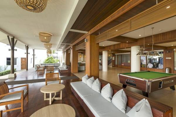 Innenbereich des Sunwing Bangtao Beach Hotels mit Loungebereich, Billardtisch und Holzmöbeln.