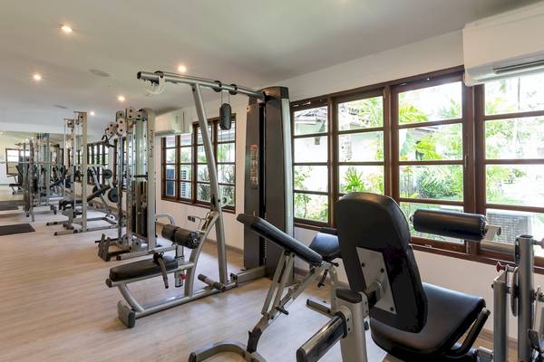 Fitnesscenter im Sunwing Bangtao Beach Hotel mit vielen Geräten und großen Fenstern.