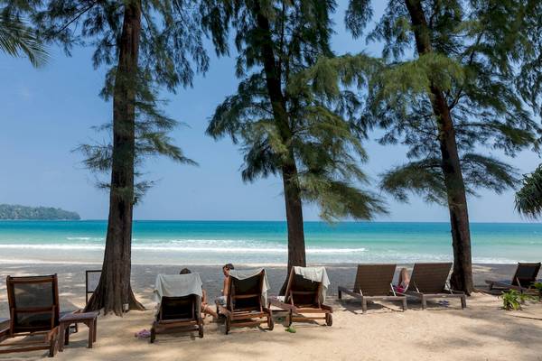 Personen entspannen auf Sonnenliegen am Strand des Sunwing Bangtao Beach Hotels.