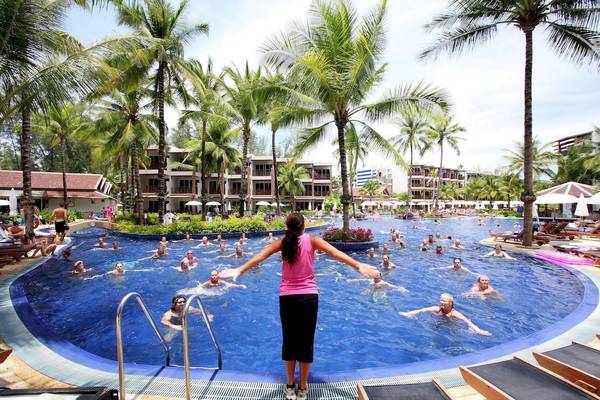 Aerobic-Kurs am Pool im Sunwing Bangtao Beach Hotel mit vielen Teilnehmern und Palmen im Hintergrund.