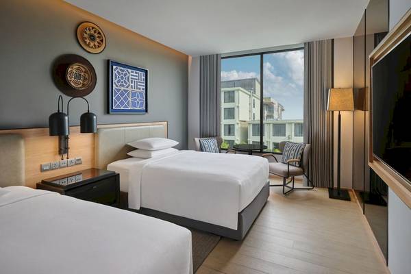 Doppelzimmer im Four Points by Sheraton Phuket Patong Beach Resort mit zwei Betten, einem Schreibtisch, Sesseln und einem großen Fenster mit Stadtblick.