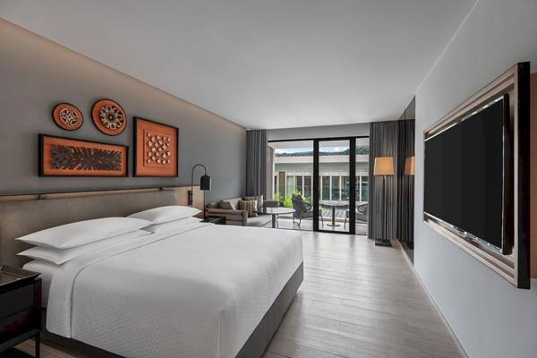 Schlafzimmer im Four Points by Sheraton Phuket Patong Beach Resort mit großem Bett und Ausblick auf den Garten.