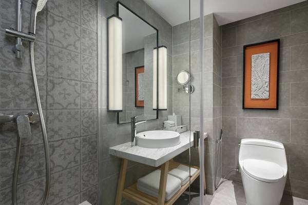 Badezimmer des Four Points by Sheraton Phuket Patong Beach Resort mit grauen Wänden, Dusche, Spiegel und Toilette.