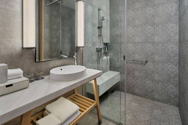 Ein Badezimmer im Four Points by Sheraton Phuket Patong Beach Resort mit grauen Fliesen, einer Badewanne und einem Waschbecken.