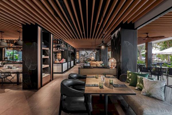 Innenansicht des Restaurants im Four Points by Sheraton Phuket Patong Beach Resort mit modernen Möbeln und braunen Holzelementen.