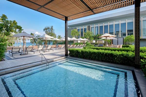 Außenpool des Four Points by Sheraton Phuket Patong Beach Resort mit Lounge-Stühlen und Sonnenschirmen