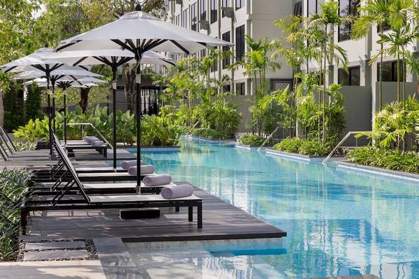 Pool im Four Points by Sheraton Phuket Patong Beach Resort mit Sonnenliegen und Sonnenschirmen.