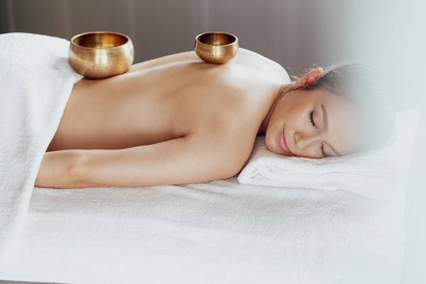 Frau mit Meditationsgloecklein auf dem Bett im Amatara Welleisure Resort