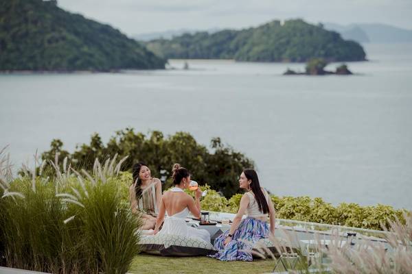Drei Frauen sitzen auf einer Terrasse mit Blick auf das Meer im Amatara Welleisure Resort.