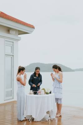 Drei Frauen beim Frühstück auf der Terrasse des Amatara Welleisure Resorts mit Blick auf das Meer.