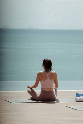 Frau in Yoga-Pose am Strand des Amatara Welleisure Resorts mit Blick auf das Meer